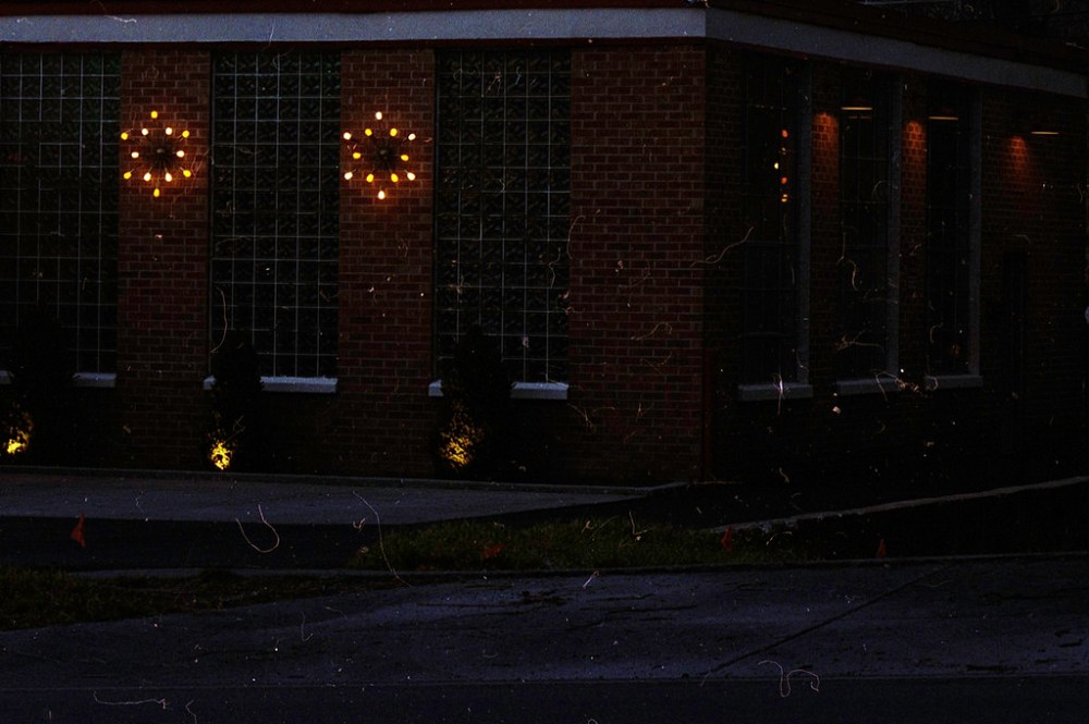 Dimly lit brick building exterior featuring decorative lighting fixtures on the walls.